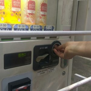 membeli minuman lewat mesin penjual minuman otomatis