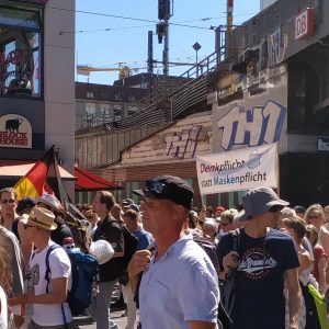 poster bertuliskan, “berpikir, bukannya mengenakan masker” yang dibawa demonstran