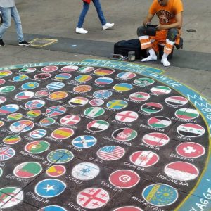 seorang artis jalanan menggambar bendera berbagai negara untuk menggambarkan keberagaman di Berlin